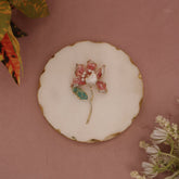 Floral brooch on a decorative plate with a pink background