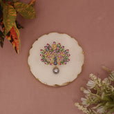 Decorative brooch on a white background with plants on a pink wall