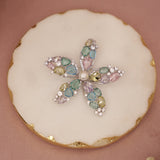 Decorative cookie with a butterfly design featuring colorful gemstones on a pink background