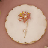 Decorative brooch with pearl and floral design on a round white and gold base.