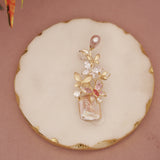 Decorative cookie with floral design and pearl-like elements on a pink background