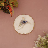Jewelry box with a decorative brooch on a pink background with green leaves.