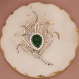 Silver brooch with green gemstone on a round white stone