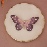Butterfly-shaped cookie with purple and gold decorations on a pink background