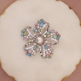 Multicolored gemstone ring with pearl center on a decorative plate