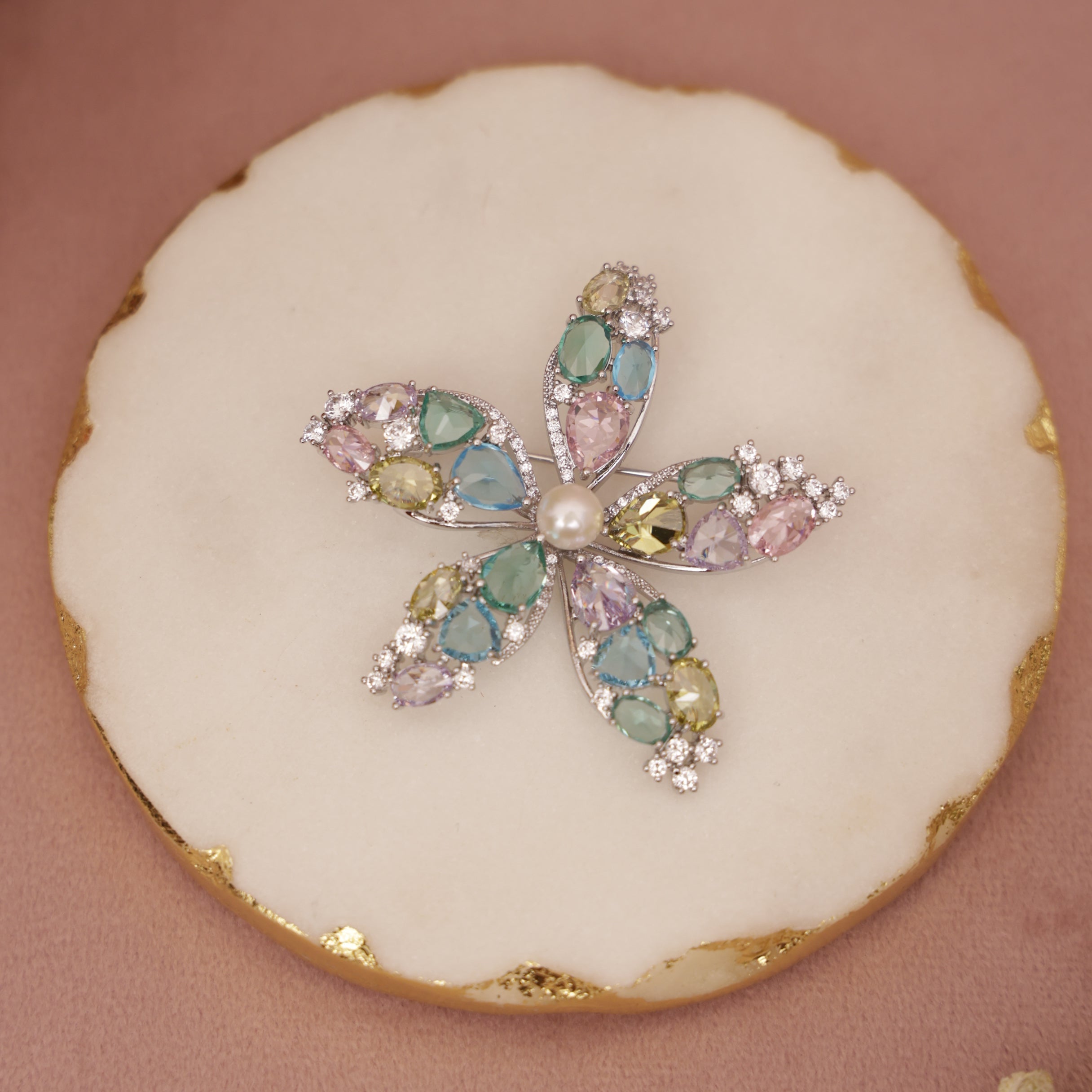 Decorative cookie with a butterfly design featuring colorful gemstones on a pink background