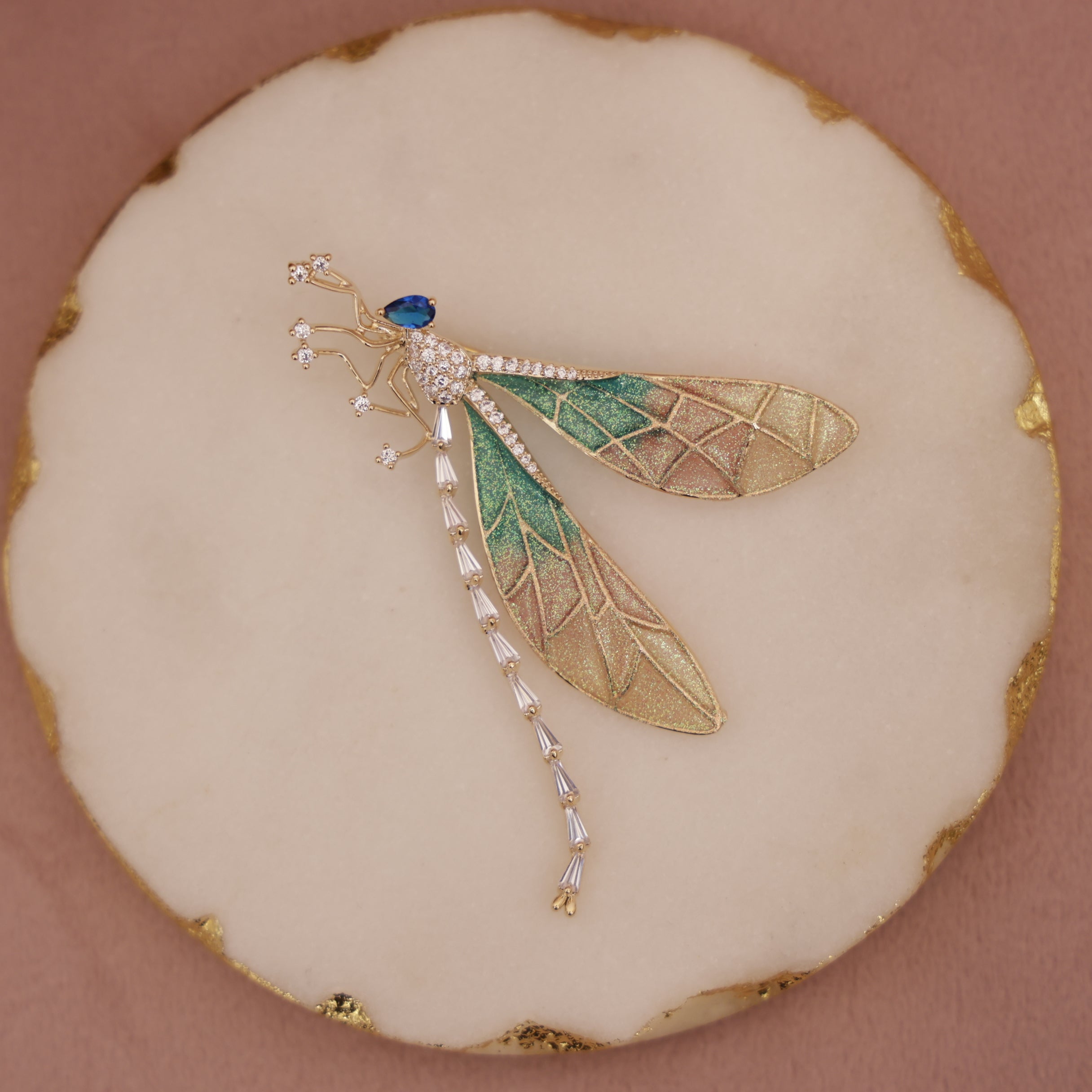 Decorative brooch with gold and green leaf design on a beige background