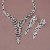 Silver necklace and earrings set on a pink background
