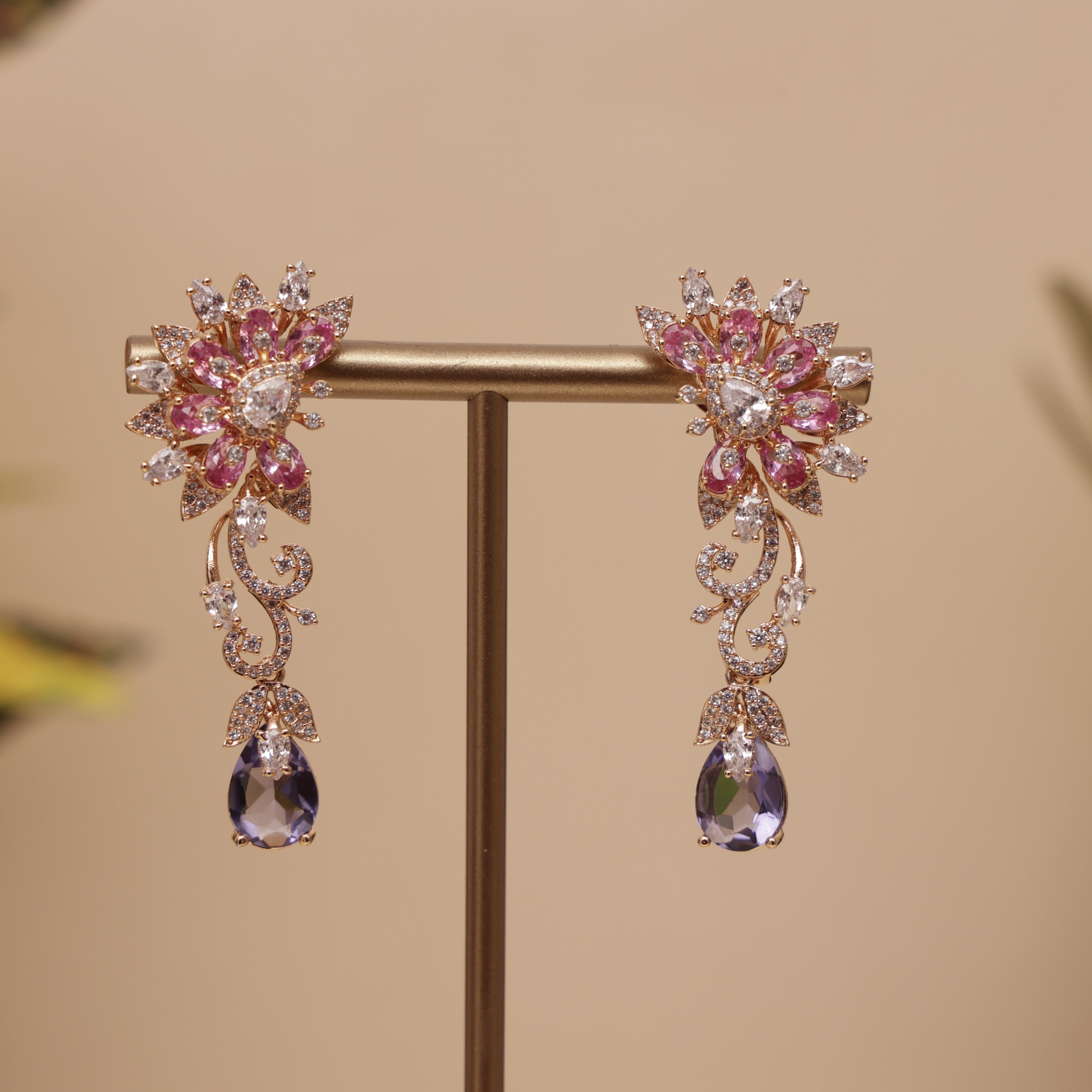 A pair of gold-toned floral drop earrings with pink and clear rhinestones, designer earring for a perfect fastival
