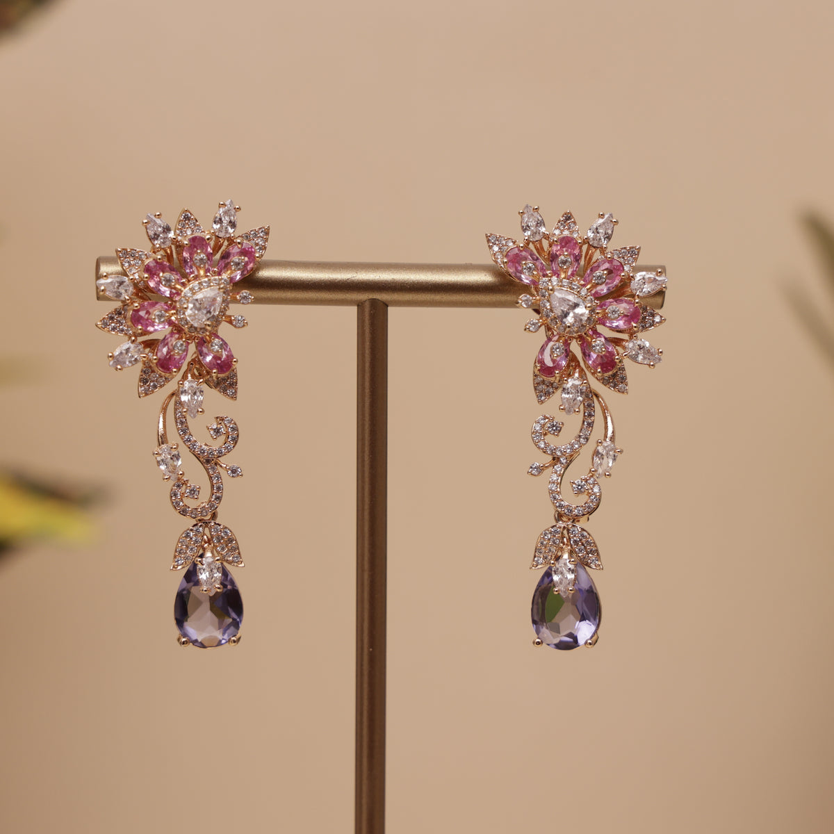 A pair of gold-toned floral drop earrings with pink and clear rhinestones, designer earring for a perfect fastival